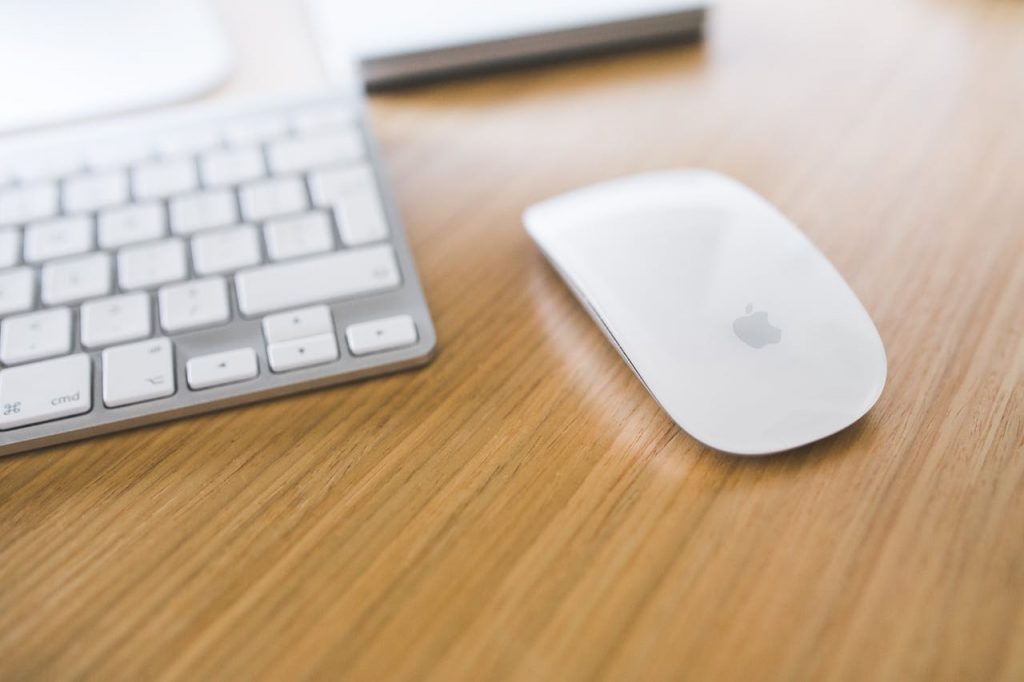 A sleek office setup featuring a wireless mouse and keyboard on a wooden desk.